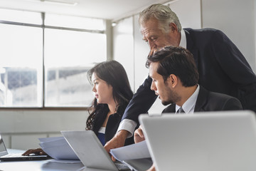 Marketing team consulting sales plan with supervisor senior manager in conference room before presenting to client.