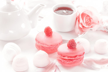 Raspberry and strawberry pink macaroons on pastel valentine decor and rose flowers soft background, shallow DOF. Gentle macaroons on table on light background