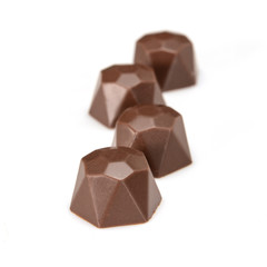 Chocolate pralines. Four dark chocolate bonbons with hazelnut fillings, macro close-up isolated on white background.