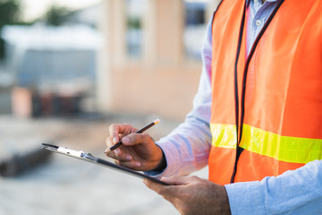 Asian inspector checking structure of new property and taking note in the clipboard for review and...