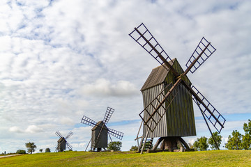 Fototapeta na wymiar Three old windmills on a green sunny field