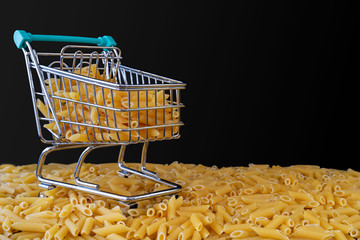 Shopping cart filled with raw pennies on a black background.
