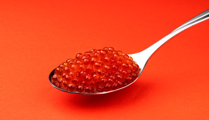 Red caviar in spoon isolated on red background