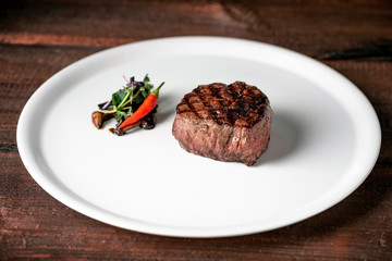 Grilled beef tenderloin Steak on a white platter with vegetables served in a restaurant.