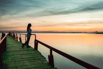 Fototapeta premium woman walking on pier at sunset