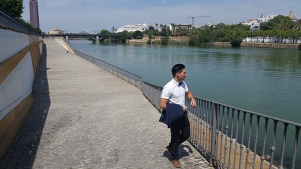joven hombre con pajarita admirando el rio guadalquivir