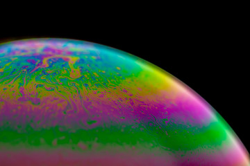 Psychedelic abstract planet from soap bubble, Light refraction on a soap bubble, Macro Close Up in soap bubble. Rainbow colors on a black background. Model of Space or planets universe cosmic galaxy.
