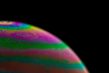 Psychedelic abstract planet from soap bubble, Light refraction on a soap bubble, Macro Close Up in soap bubble. Rainbow colors on a black background. Model of Space or planets universe cosmic galaxy.