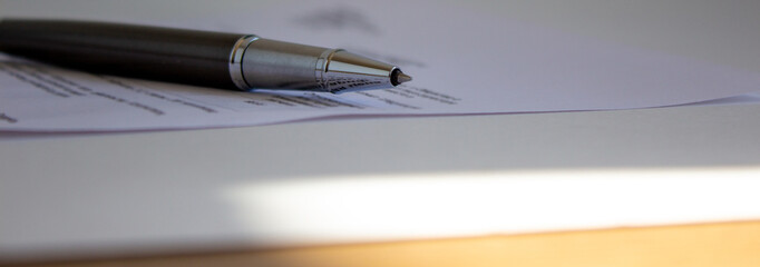 Document and pen on beautiful white table. Warm sunlight. Concept background.