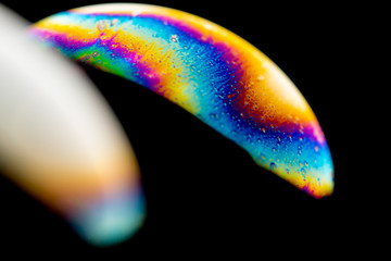 Psychedelic abstract planet from soap bubble, Light refraction on a soap bubble, Macro Close Up in soap bubble. Rainbow colors on a black background. Model of Space or planets universe cosmic galaxy.