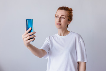 Woman smiling, wearing a white T-shirt, using a mobile phone isolated on a white background