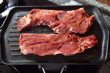 Bistecche ( costata di vaccino) pronte per essere  arrostite sulla piastra in ghisa sui fornelli di casa 