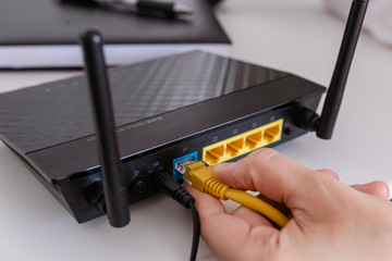  woman connects the internet cable to the router's socket. Fast and wireless internet concep