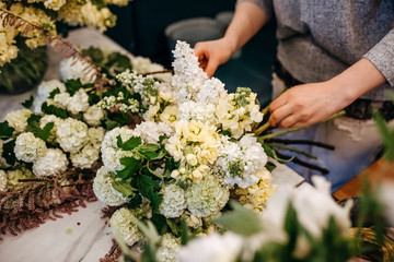 Process of making a bouquet of seasonal flowers. Female florist making bouquet in flower shop.