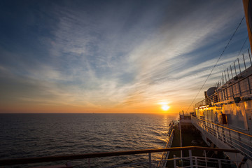 Spectacular sunset over the sea horizon seen from the upper deck of a cruise ship, Adriatic sea, Italy. Concept: luxury cruise, navigation, maritime transport, sunrise on sea, relaxation on sea
