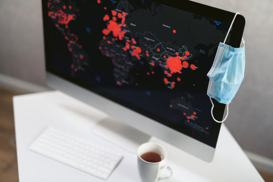 Office computer with a map of the spread of coronavirus infection. Covid 19 world map. Medical disposable face mask as a symbol of outbreak and quarantine