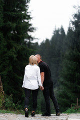 A man next to a woman, guy and a girl are standing close, touching each other, holding hand on forest background. Boy and girl, couple. Intimacy, honesty, trust. Bright future. Couple