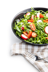 Fresh arugula salad with radishes, tomatoes and red peppers.