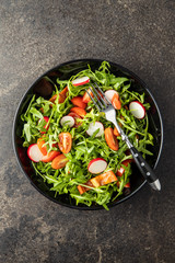 Fresh arugula salad with radishes, tomatoes and red peppers.