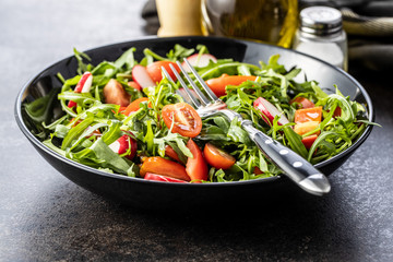 Fresh arugula salad with radishes, tomatoes and red peppers.