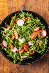 Fresh arugula salad with radishes, tomatoes and red peppers.