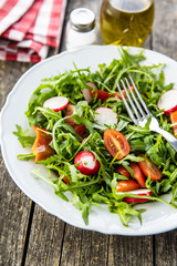 Fresh arugula salad with radishes, tomatoes and red peppers.
