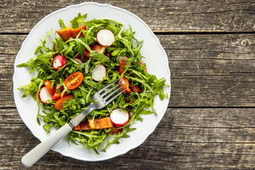 Fresh arugula salad with radishes, tomatoes and red peppers.