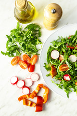 Fresh arugula salad with radishes, tomatoes and red peppers.