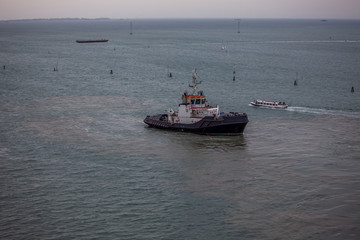 Tugboat engaged in the docking of a ship in the port of Venice, Italy. Concept: maritime transport, commerce, shipbuilding industry, maritime trade