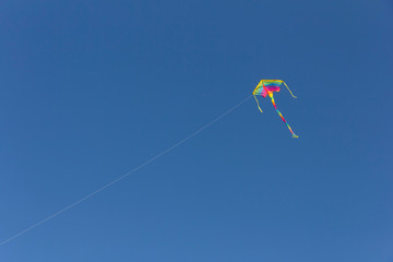 Colorful ribbons and kite figures hanging on poles and flying on blue sky background kite festival