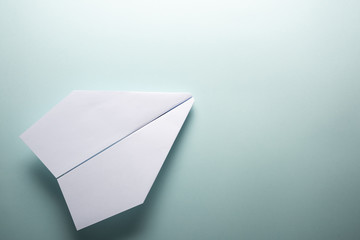 White paper airplane on a turquoise background