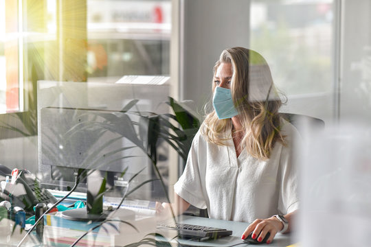 Executive woman working at her desk and wearing a protective mask against covid-19