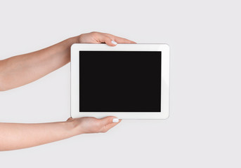 Closeup of girl holdng tablet computer with empty screen on light background, mock up for design