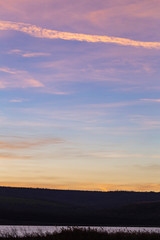 Purple-magenta clouds. Landscape with bloody  dawn. The terrain in southern Europe.  Panorama. Mirror lake with a reflection of nature. Morning silence. Water surface.