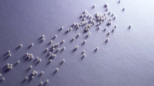 White granules of medicine crumble on a white background close-up slow motion. Homeopathy medicin granules isolated. healtcare and pills concept