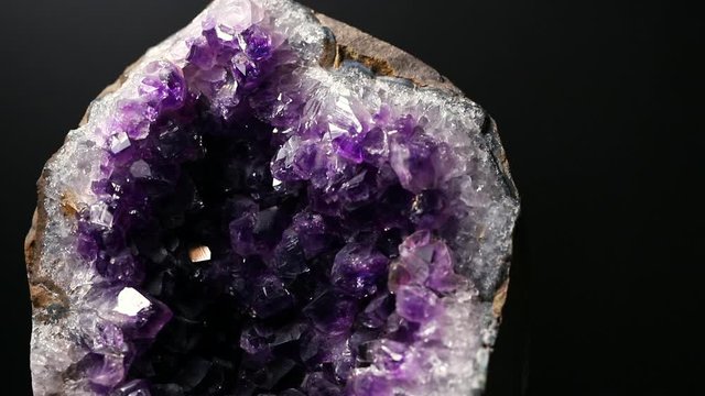 Iridescent light on an amethyst druzy stone. Macro footage.