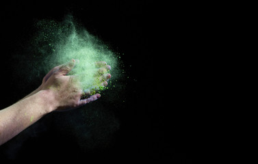 Fototapeta na wymiar Green cloud of paint around hands on black background