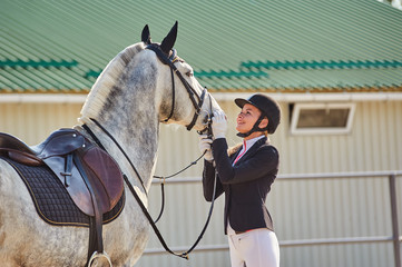 Girl horse rider stroking a horse. Equestrian theme