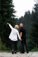 A man next to a woman, guy and a girl are standing close, touching each other, holding hand on forest background. Boy and girl, couple. Intimacy, honesty, trust. Bright future. Couple