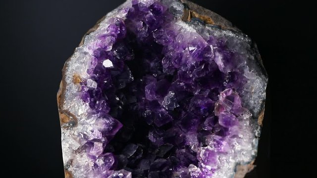 Iridescent light on an amethyst druzy stone. Macro footage.