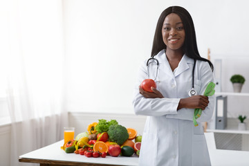 Friendly black woman dietician with apple and tape