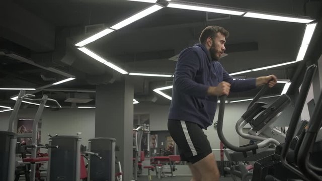 The man with the beard is engaged in the simulator stepper during a workout.