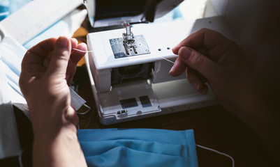 Close up sewing medical masks during the epidemic of the coronavirus Covid-19 pandemic. An elderly woman sews masks at home to protect against the spread of infection. Quarantine and self-isolation