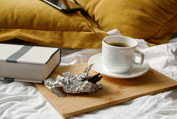 coffee with chocolate reading a book in bed. yellow pillows.