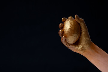 Minimalism concept. Hand holds lemon in gold paint