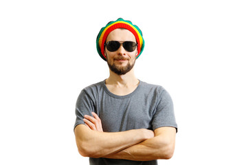 Young caucasian smiling man in rasta hat, sunglasses and grey t-shirt on white background laughing...