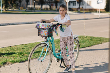 beautiful girl on a blue bicycle. girl rides a bicycle. summer holidays. spend time with benefit. female bicycle with basket