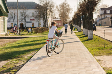 Obraz premium beautiful girl on a blue bicycle. girl rides a bicycle. summer holidays. spend time with benefit. female bicycle with basket
