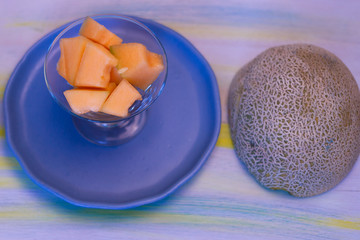 Melon pieces, on white table with blue plate.
