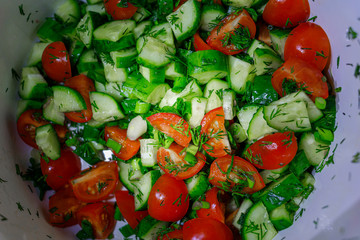 cucumbers and tomatoes onion dill parsley chopped for salad are in a pot, taken close-up